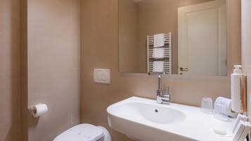 Un bagno con lavandino, water e portasciugamani bianchi.