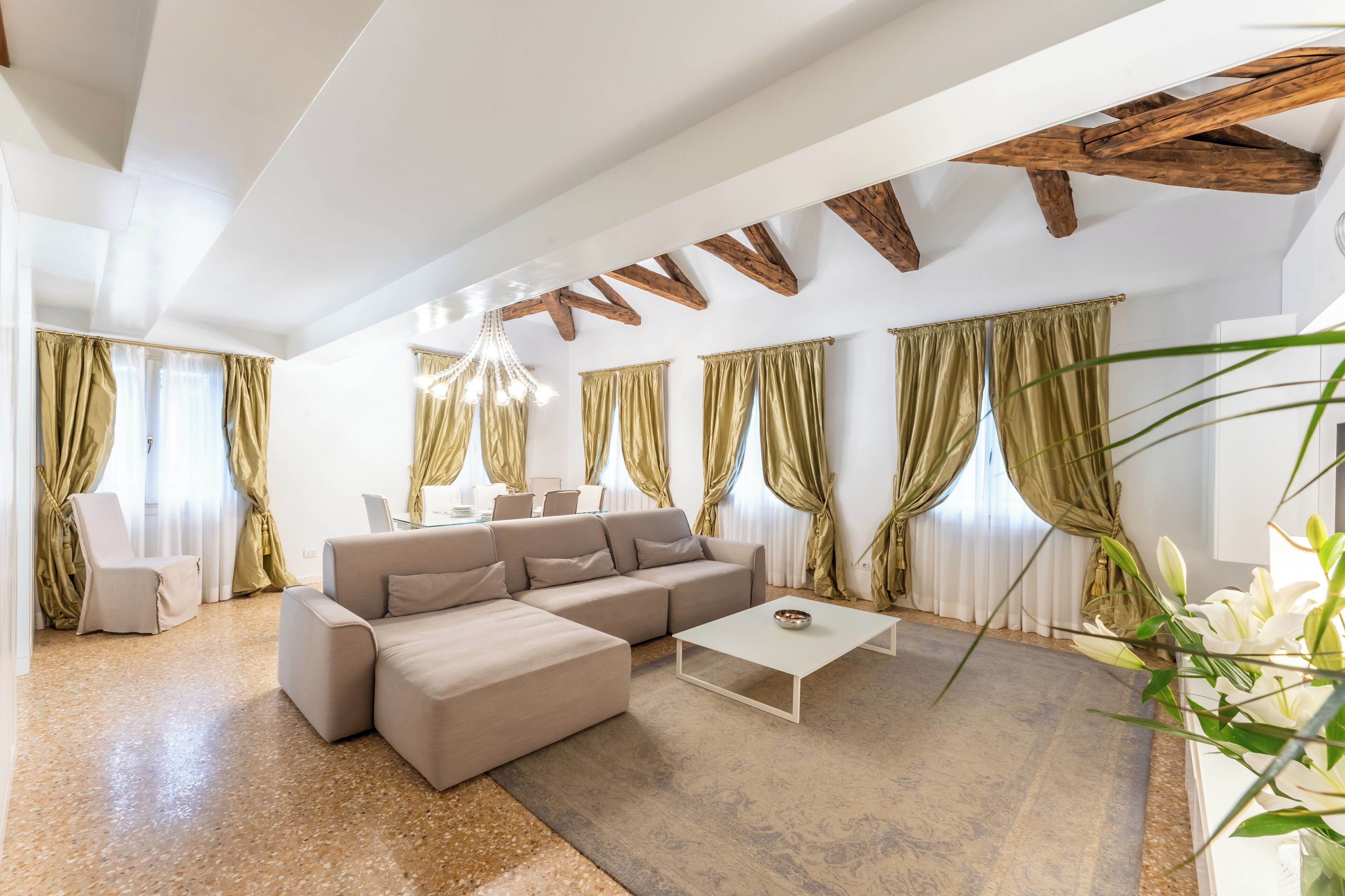 Ein modernes Wohnzimmer mit einem beigefarbenen Ecksofa, einem weißen Couchtisch und einer Kronleuchter.