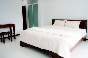 Un dormitorio con una cama de madera, una mesita pequeña de madera y una puerta verde.