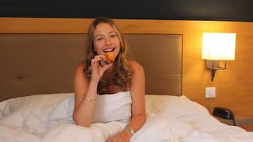 A hotel room with a bed, a tray with breakfast items, and a magazine on the bed.