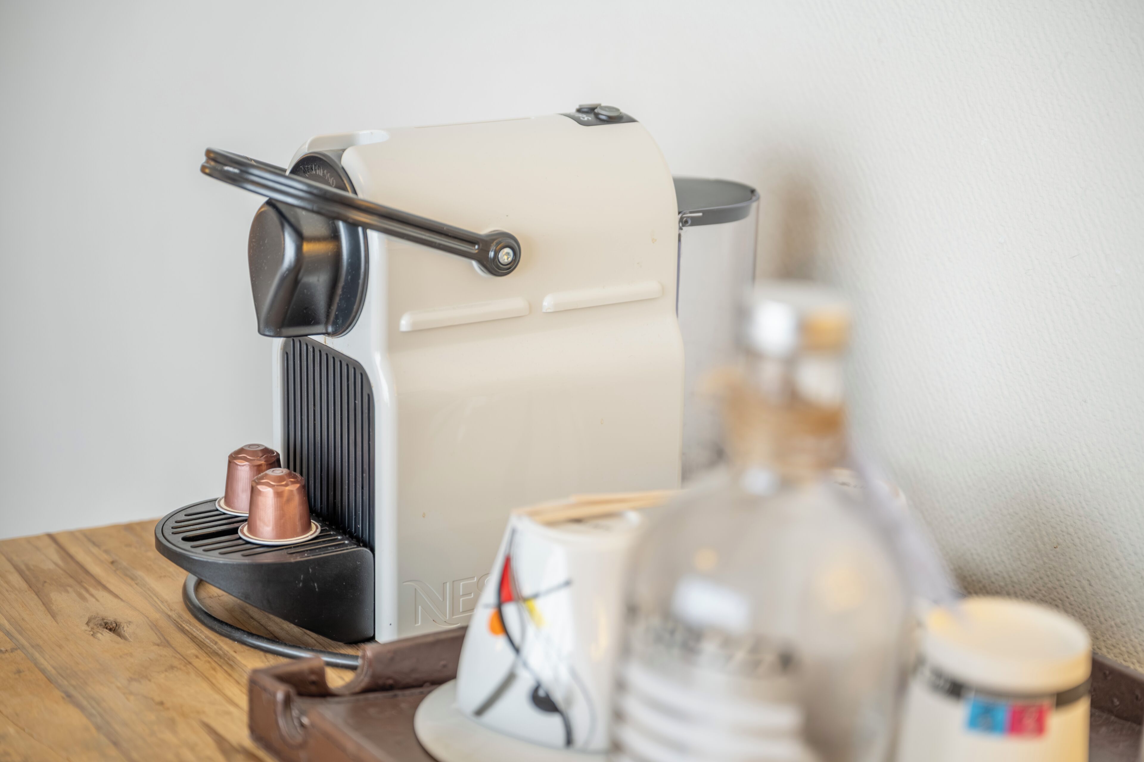 A vintage espresso machine on a wooden table with a glass jar and a ceramic mug.