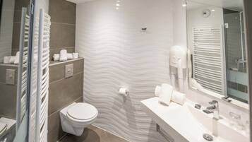 A modern bathroom with a white sink, mirror, and towel rack.