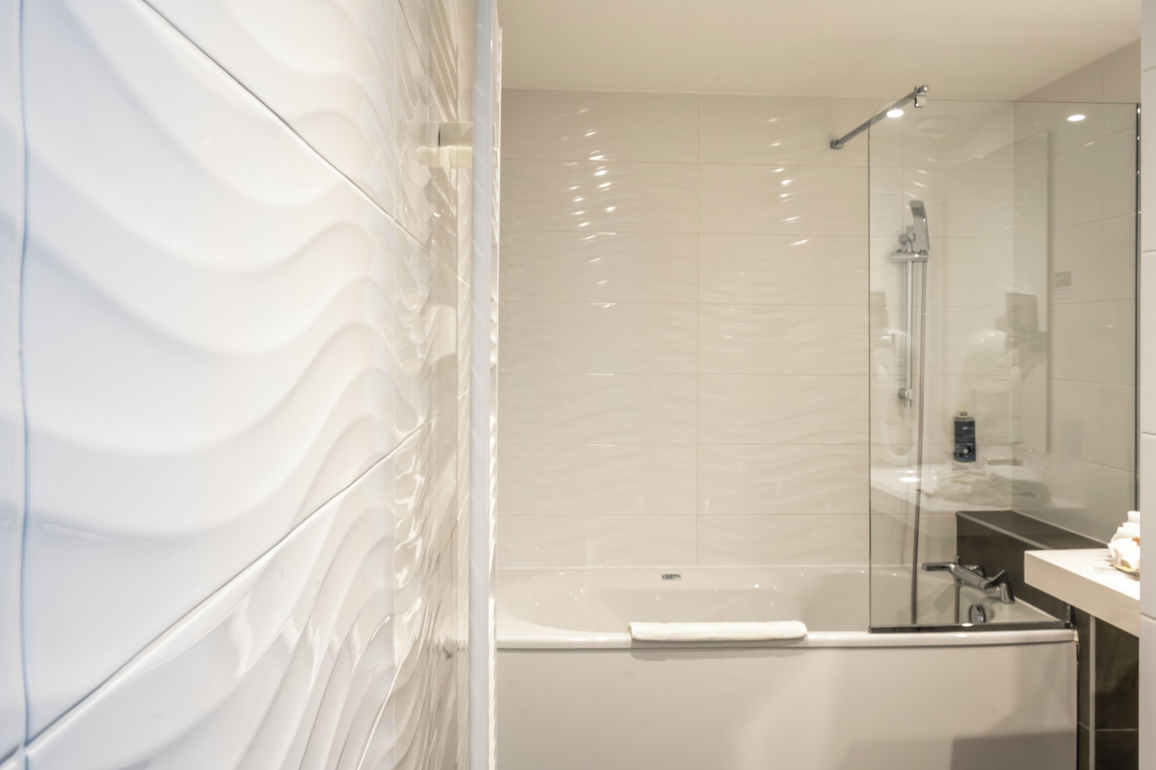Ein modernes Badezimmer mit einer gläsernen Duschkabine, einer weißen Badewanne und einem Waschtisch mit Spiegel.