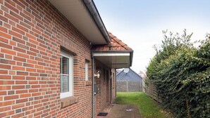 Ein Backsteinhaus mit überdachter Veranda und einem Weg zu einer Grünfläche.