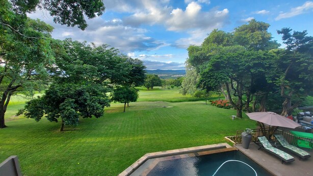 Um quintal com piscina, gramado e vista para um campo de golfe.