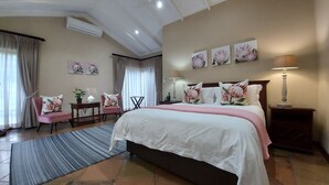 Quarto de hotel com uma cama grande, uma escrivaninha, uma cadeira e um abajur.