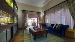 Uma sala de estar com um sofá azul, uma mesa de centro de madeira e um aquário.