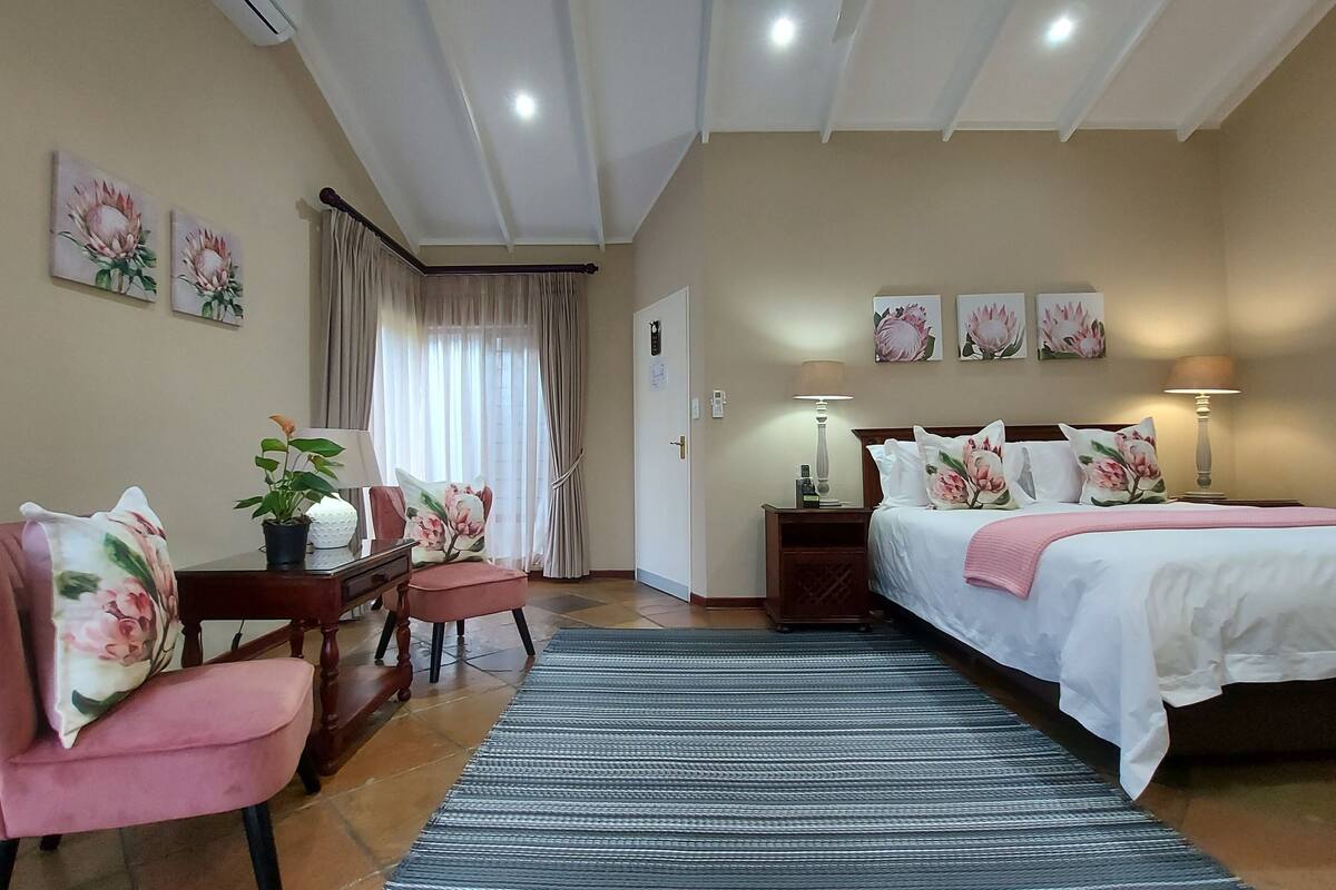 Ein Hotelzimmer mit Bett, Schreibtisch mit Stuhl, Lampe und einer Zimmerpflanze.