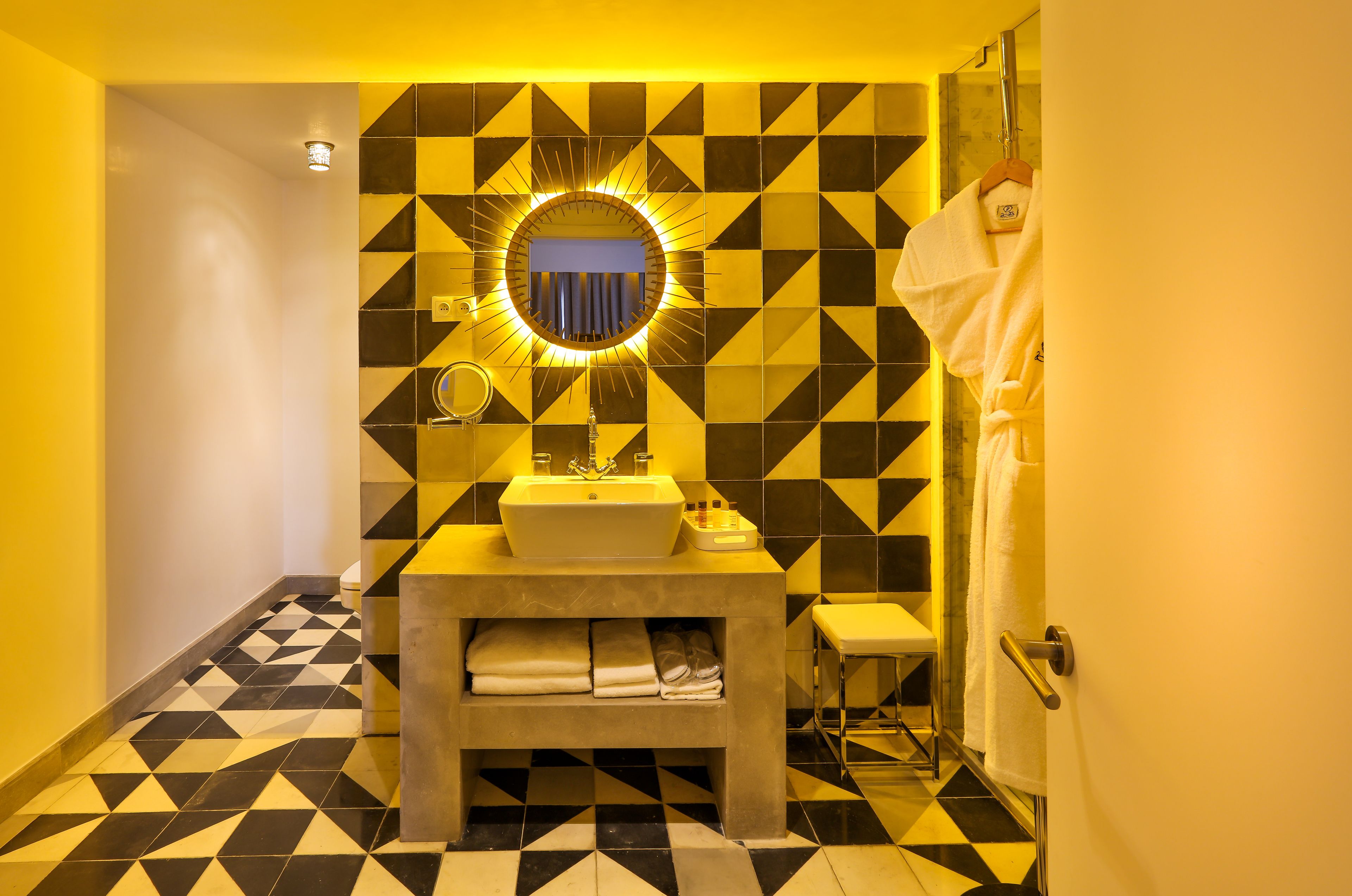 A bathroom with a geometric patterned floor, a sink with a mirror, and a towel rack.