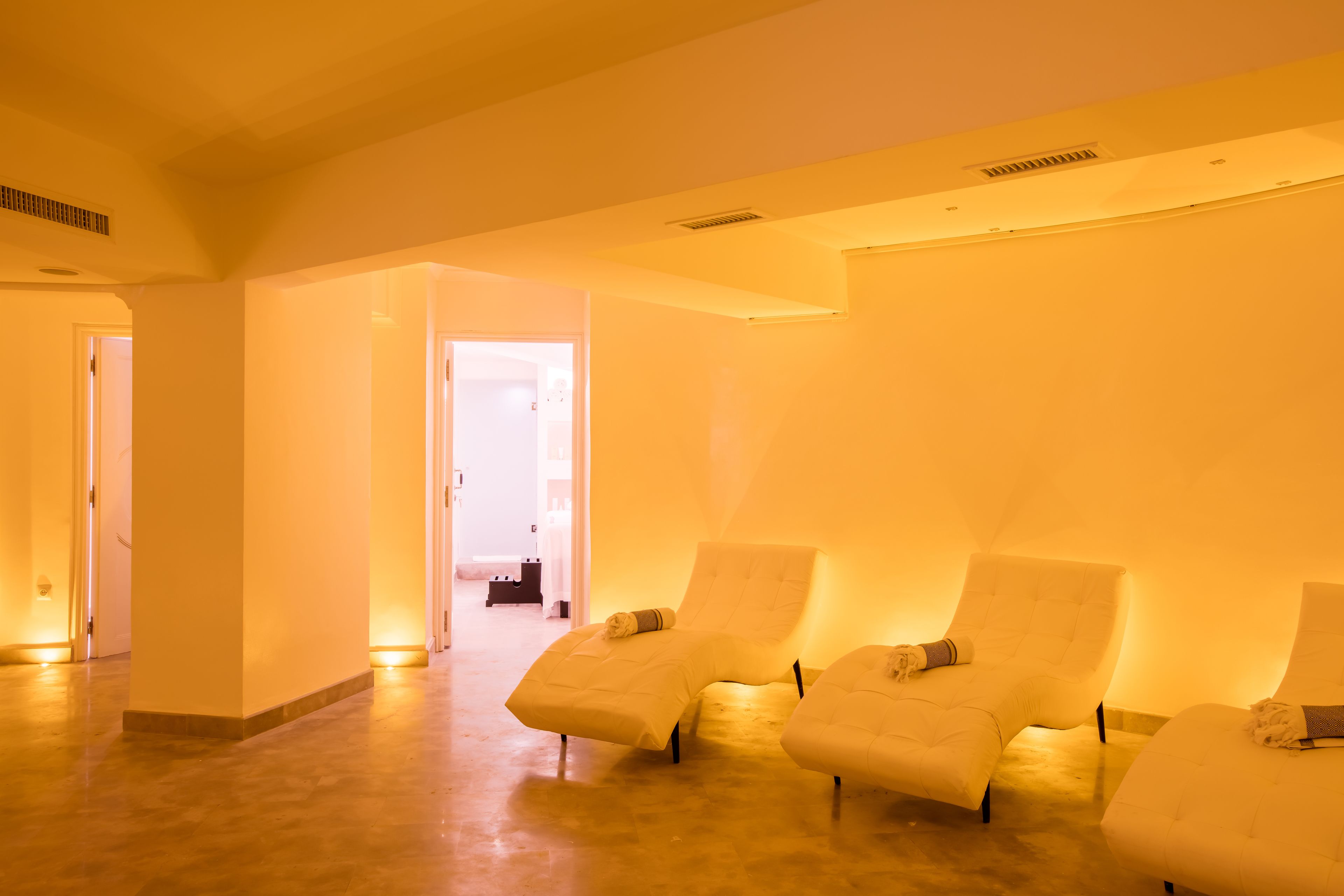 Un cuarto de spa con tres sillas reclinables, una puerta que da a otra habitación y un suelo de color claro.
