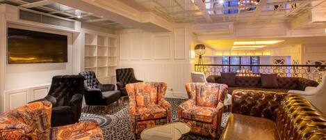 A spacious lounge area with patterned armchairs, a leather sofa, and a large flat-screen TV.