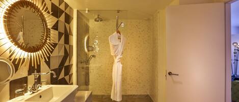 A modern bathroom with a large mirror, a sink, and a shower area.