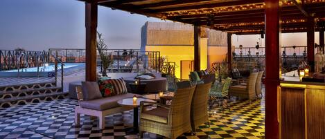 Terraza en la azotea con suelo a cuadros, mobiliario exterior y vistas a una piscina.