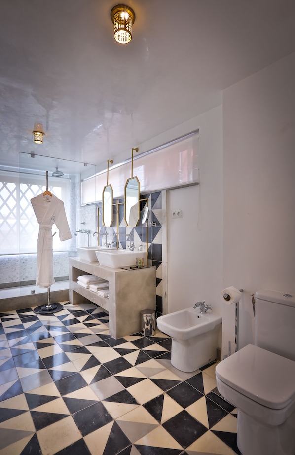 A modern bathroom with a black and white checkered floor, a large mirror, a robe hanging, and a sink with a bidet. - 2Ciels Boutique Hotel & SPA (Marrakech)