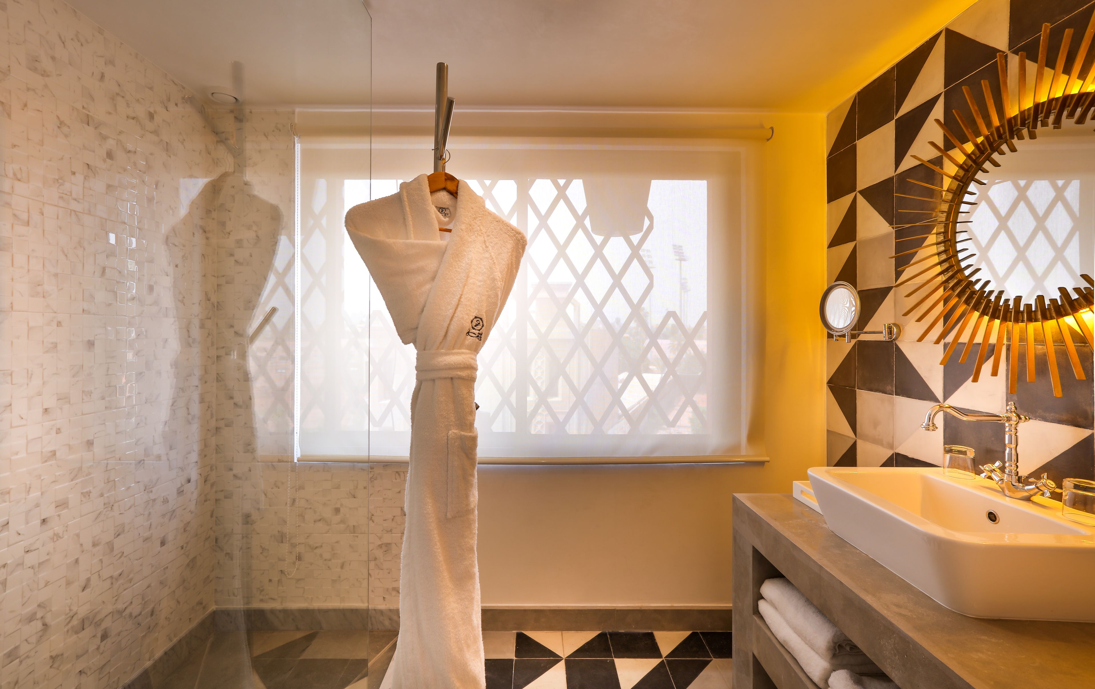 Un baño con una bañera blanca, un lavamanos con espejo y una ventana con diseño geométrico.
