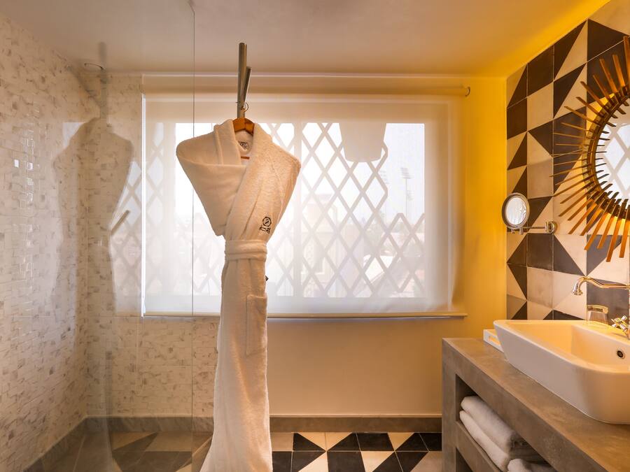 Un baño con una bañera blanca, un lavamanos con espejo y una ventana con diseño geométrico.