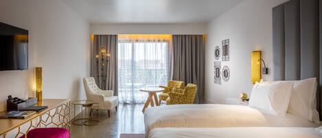 Une chambre d’hôtel avec un grand lit, un bureau avec un ordinateur, une chaise, une petite table et un téléviseur.