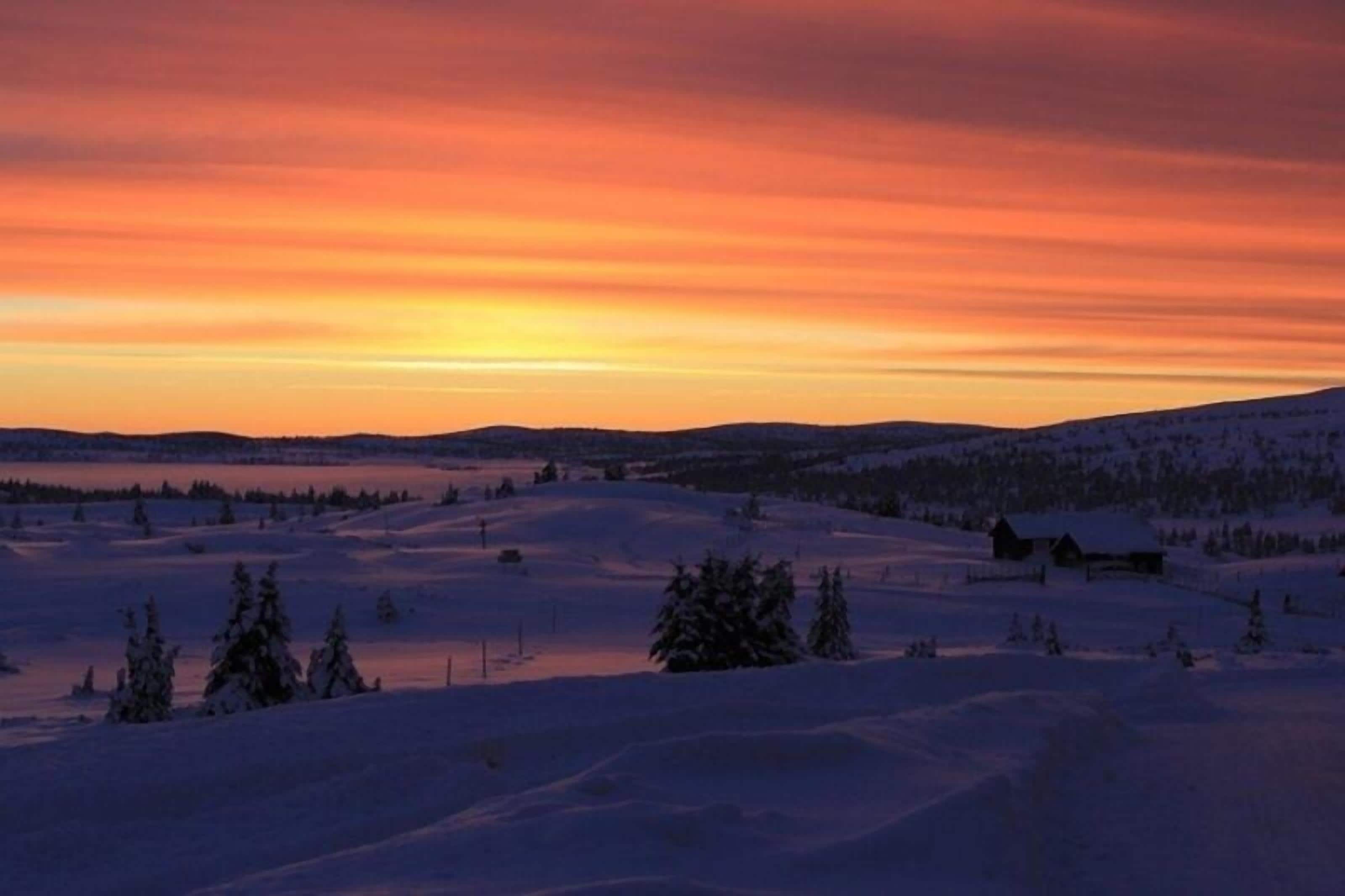 Lumipeitteinen maisema auringonlaskun aikaan.