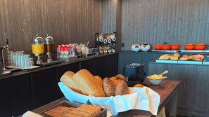 Ein Buffet mit verschiedenen Brotsorten, einem Saftspender und einem Toaster.