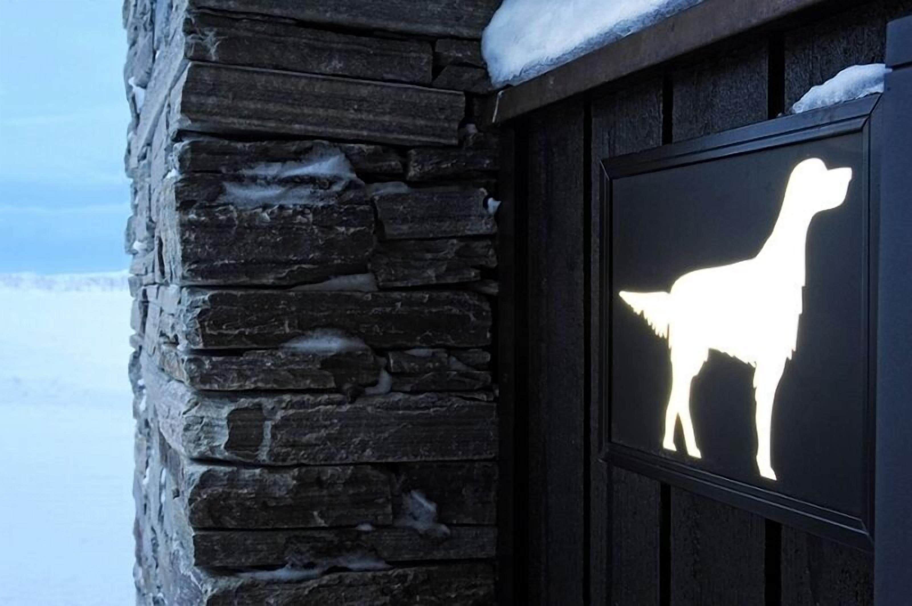 Un mur de pierre sur lequel est peint, sur une plaque, la silhouette d’un chien.