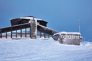 Ein mit Schnee bedecktes Gebäude mit einer Steinwand und einem Schild mit der Aufschrift "Pellestova".