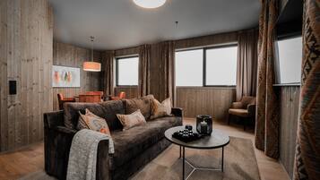 A modern living room with a dark brown sofa, a round coffee table, and a wooden accent wall.