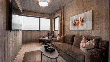 Una sala de estar moderna con techo de madera, un ventanal grande, un sofá, una mesa de centro y un cuadro en la pared.