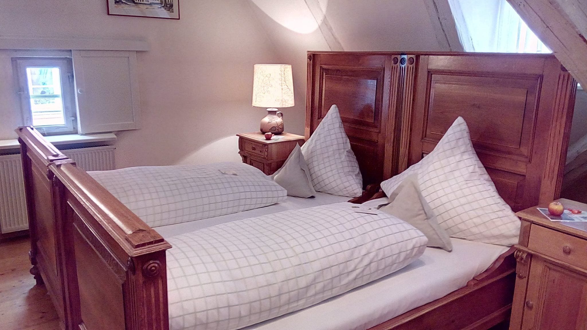 Un dormitorio con cama de madera, mesita de noche con lámpara y ventana con vistas.