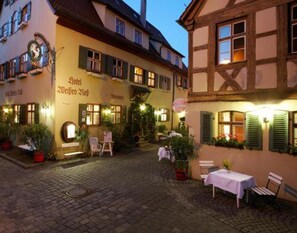 A traditional European courtyard with a restaurant named "Hotel Weisses Hof" and a small outdoor seating area with tables and chairs. - Hotel Weisses Ross (Dinkelsbuehl)