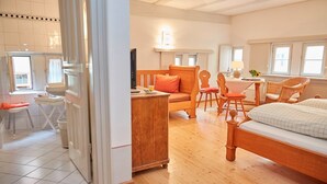 A spacious bedroom with a wooden bed, a desk with a chair, a sofa, and a dining table with chairs. - Hotel Weisses Ross (Dinkelsbuehl)