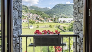 Ein Balkon mit einer Steinmauer, Blick auf eine Stadt und roten Blumen.