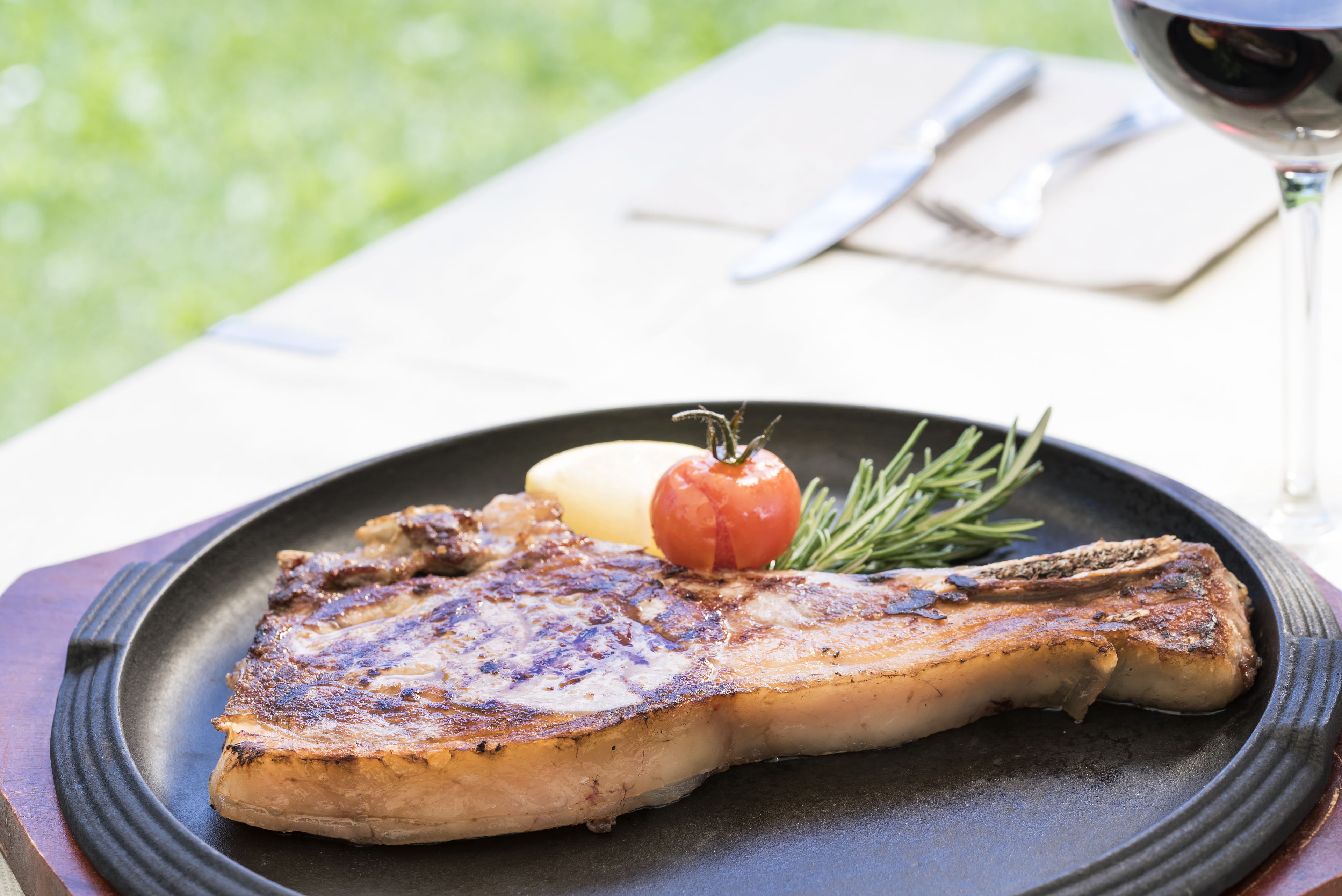 Een gegrilde steak met gebakken aardappel en een tomaat op een bord.