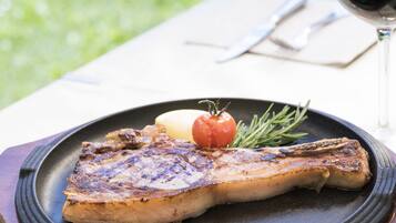 Een gegrilde steak met gebakken aardappel en een tomaat op een bord.