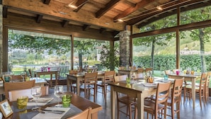 Ein Restaurant mit Holztischen und -stühlen, großen Fenstern und einer Steinsäule.
