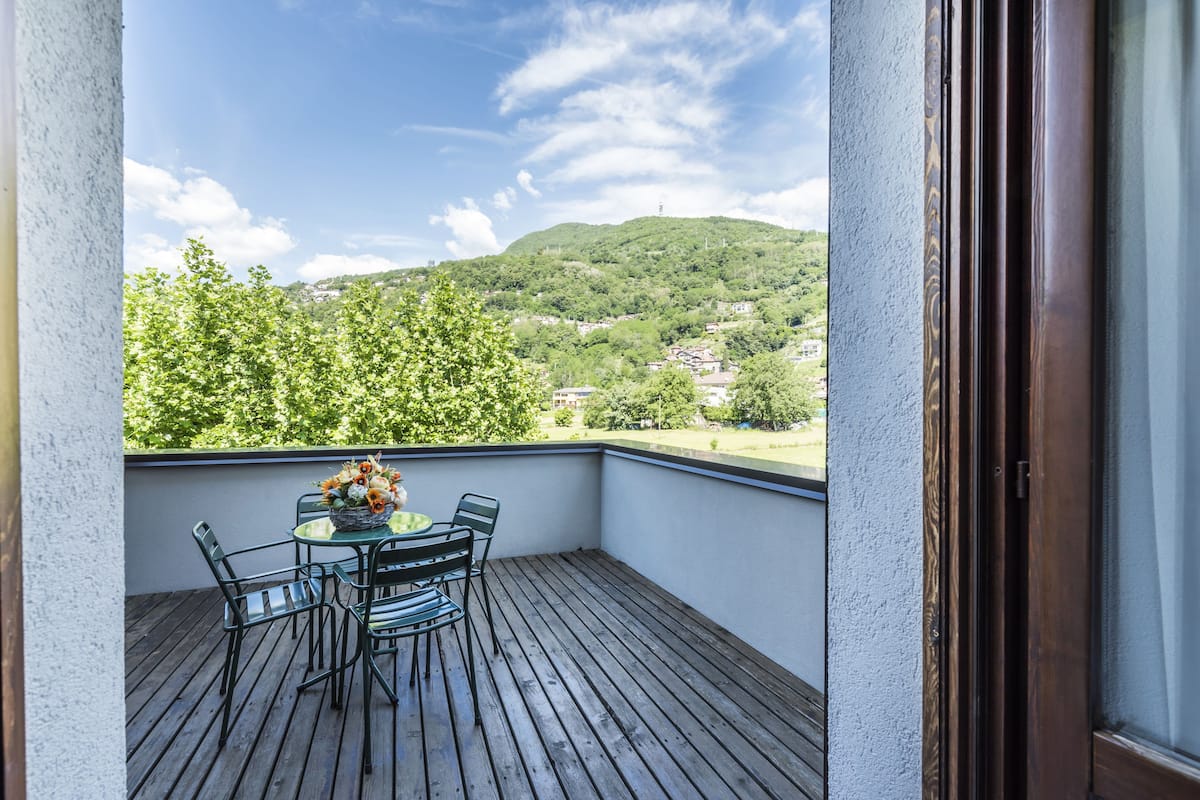 Ein Balkon mit Holzboden, einem Tisch mit Stühlen und einem Blumenstrauß.
