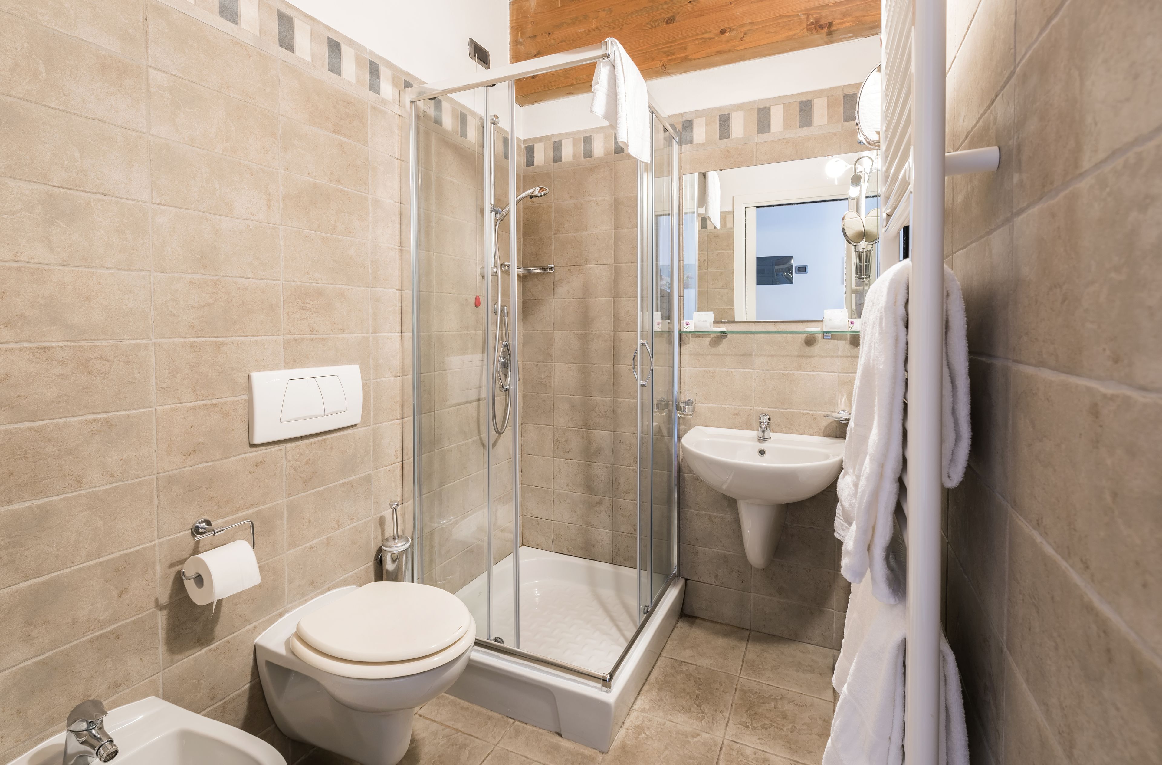 A modern bathroom with a glass-enclosed shower, a toilet, a sink, and a towel rack.