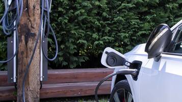 A Tesla vehicle charging at a station with a sign indicating electric vehicle charging.