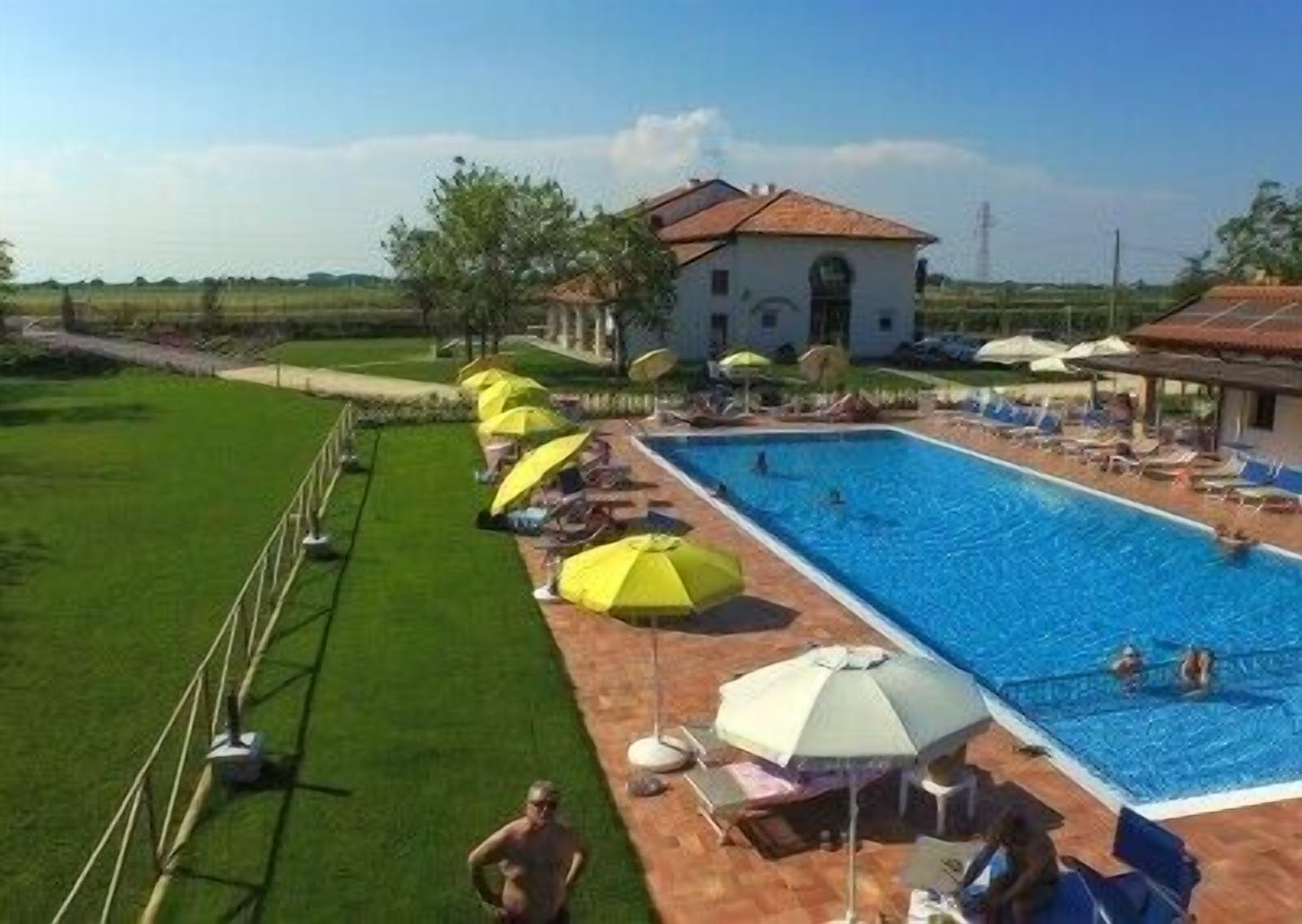 Ein Swimmingpool mit Sonnenschirmen, Liegestühlen und einem Gebäude im Hintergrund.