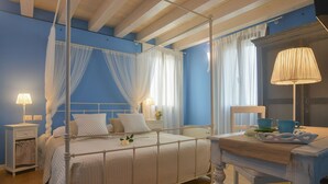 Un dormitorio con cama con dosel, una mesita de noche con lámpara y un espejo sobre un aparador de madera.