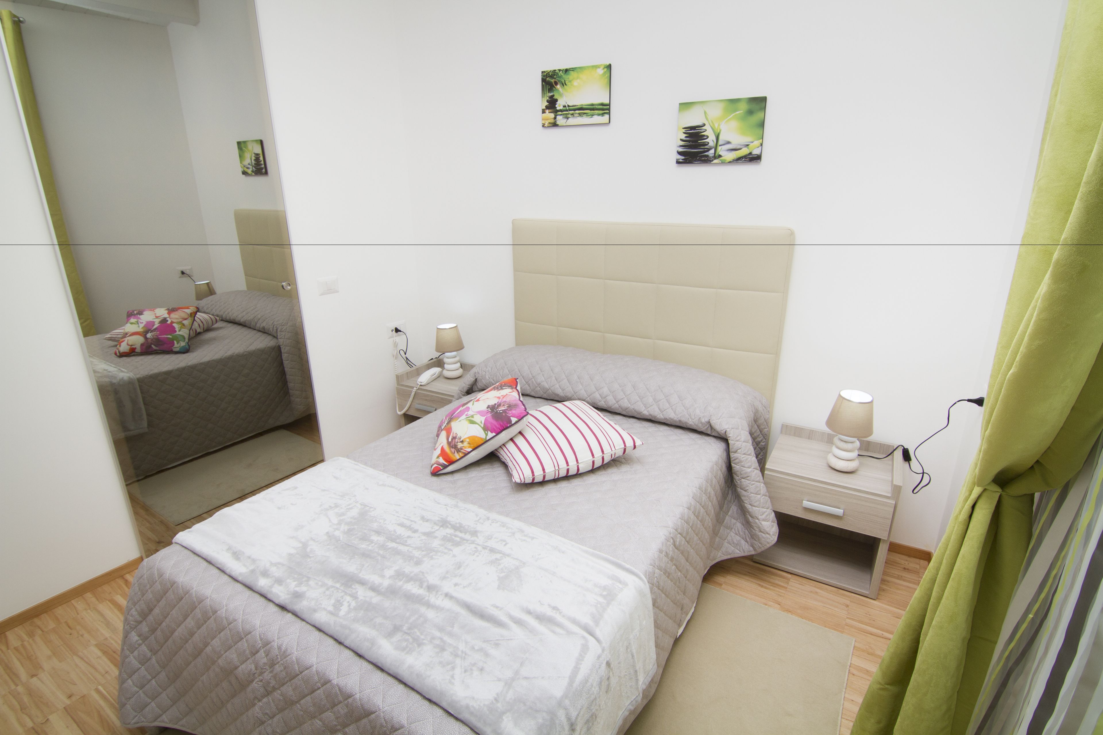 A bedroom with a bed, bedside table, lamp, and artwork on the wall.