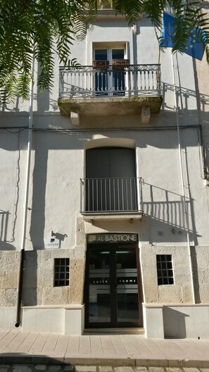 Un edificio con un letrero que dice "Al Bastione" y "habitaciones suite", indicando un hotel o establecimiento de hospedaje.