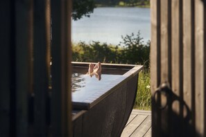 A wooden deck with a rectangular pool, surrounded by greenery and a body of water. - Marholmen (Norrtälje)