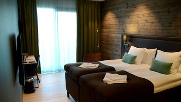 Een hotelkamer met twee bedden, een bureau en een televisie.
