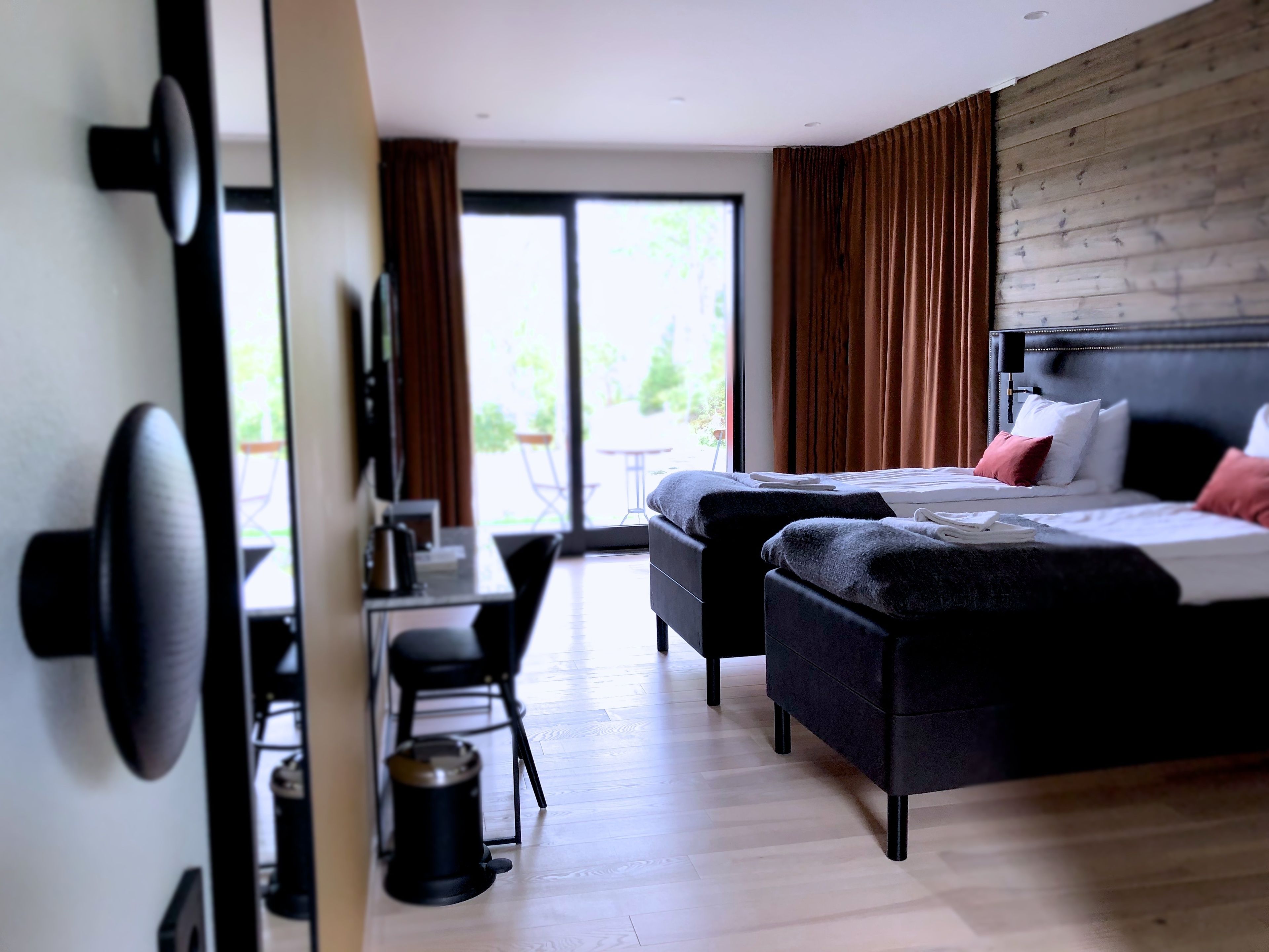 Habitación de hotel con cama, escritorio y silla. Cuenta con ventana con cortinas y vistas al exterior.