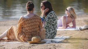 Tres personas sentadas en la playa con un sombrero y una manta.