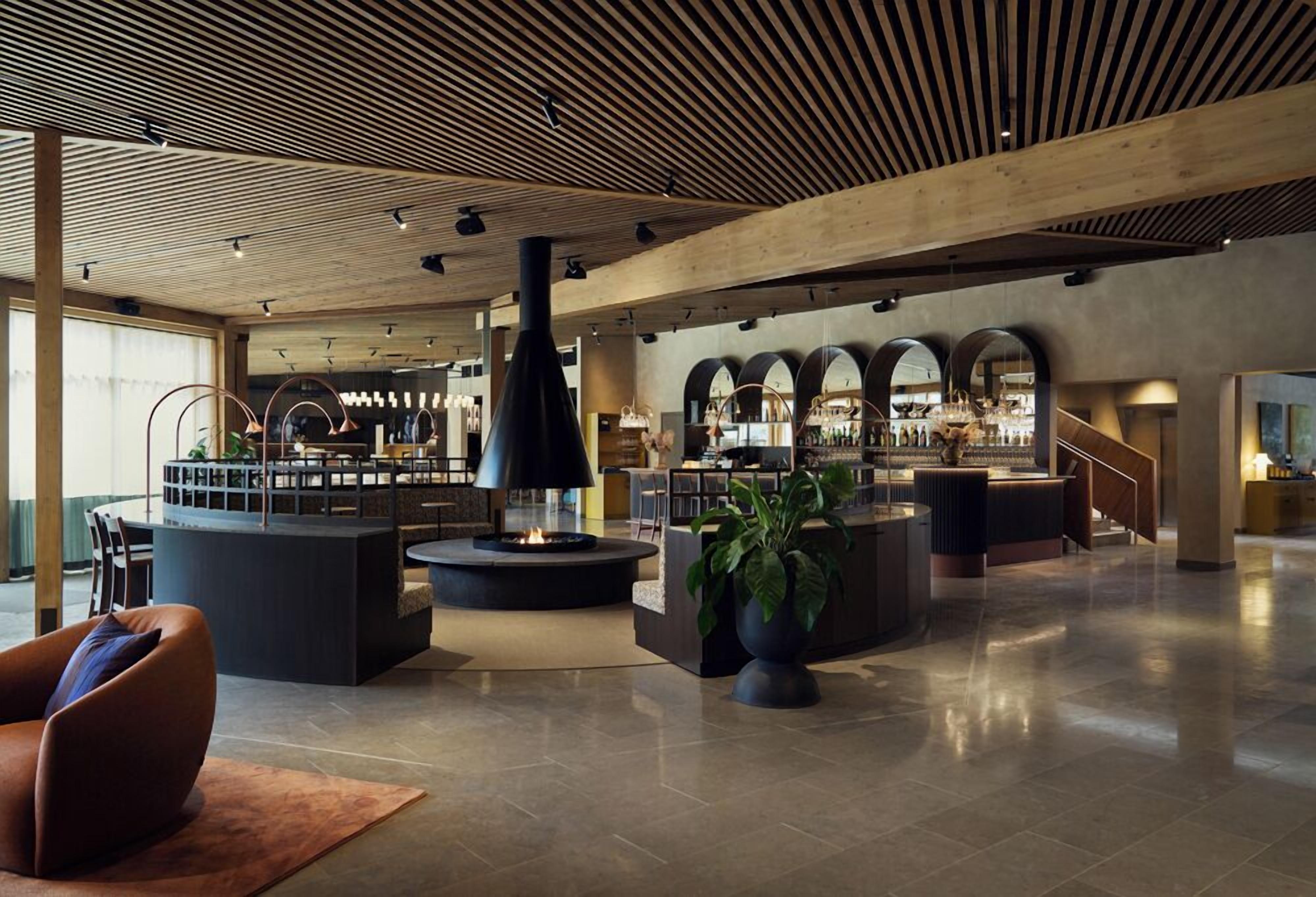 Eine geräumige Lobby mit einer zentralen Sitzecke, einer Bar mit Bogenfenstern und einem modernen Deckenstil.