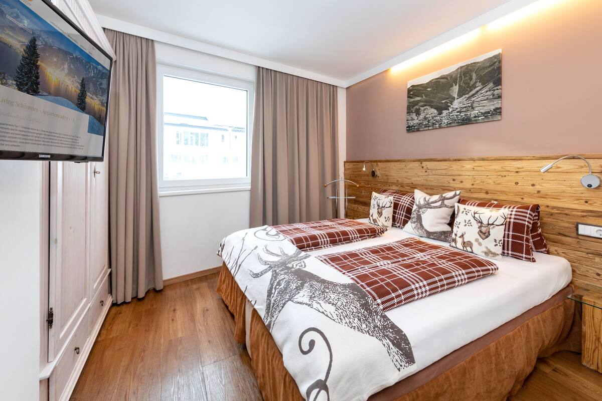 A hotel room with a large bed, wooden headboard, and a mounted TV on the wall.