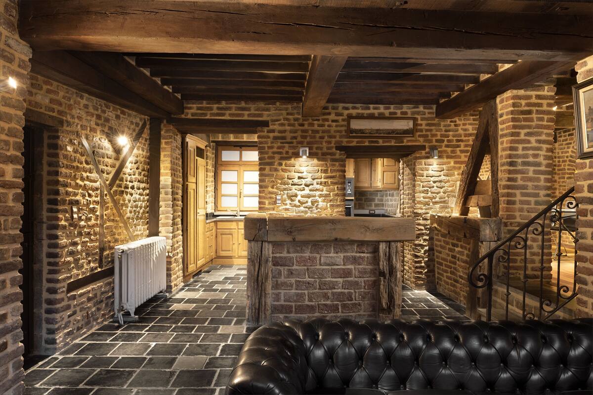 A rustic stone kitchen with a wooden bench in the foreground.