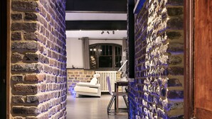 A hallway with brick walls and a tiled floor, leading to a seating area with a sofa and a table. - Appart-Hotel Léopold Liège Centre (Liege)