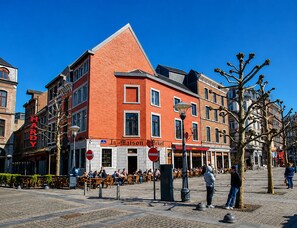 A multi-story building with a prominent red facade, a visible restaurant named 'La Maison Fleket,' and a 'HARDY' sign on the left. - Appart-Hotel Léopold Liège Centre (Liege)